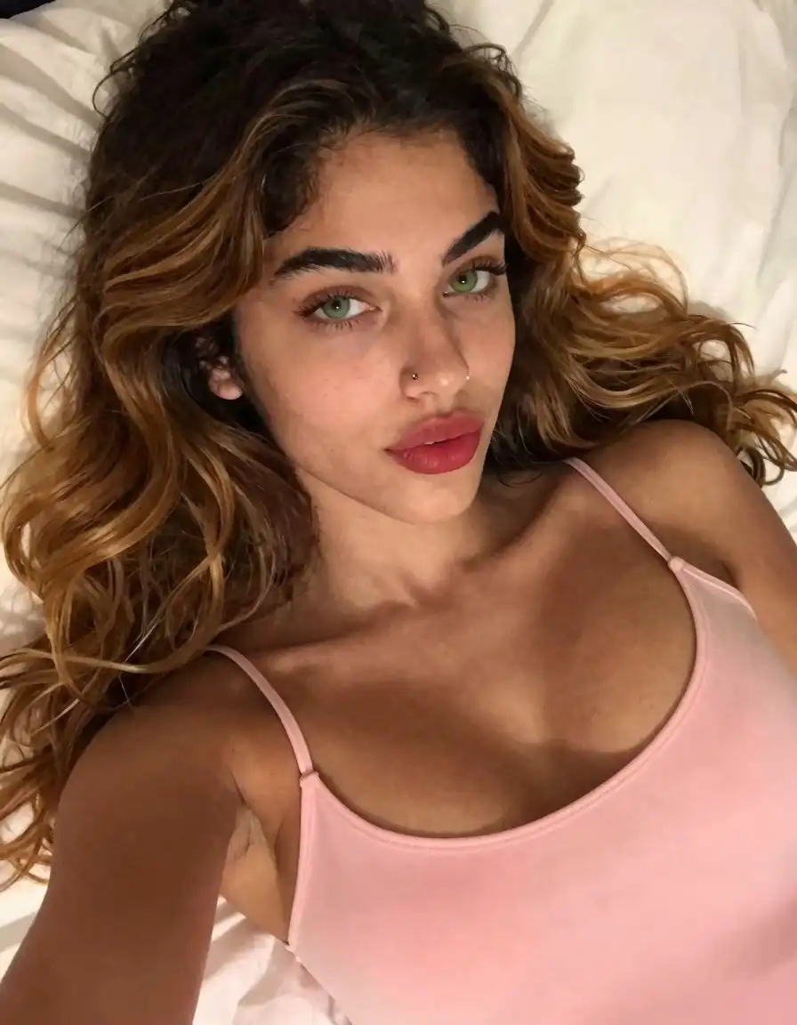 Z-Image Turbo image: A candid, high-angle close-up smartphone selfie of a 21-year-old Italian-Latina woman with warm olive skin, lying on her…